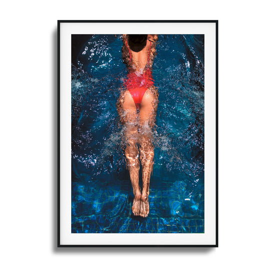 Swimmer in a red swimsuit diving into water, with dynamic splashes of water, representing grace and motion.