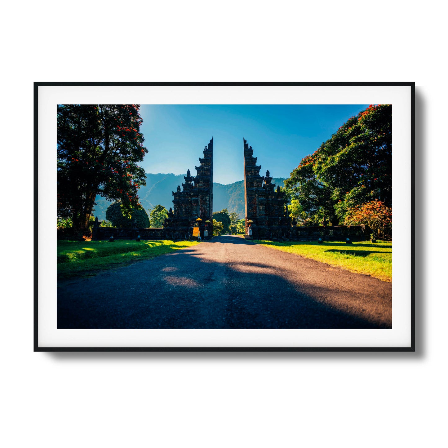 Balinese gates with a scenic mountain backdrop, surrounded by trees and sunshine, framed art.