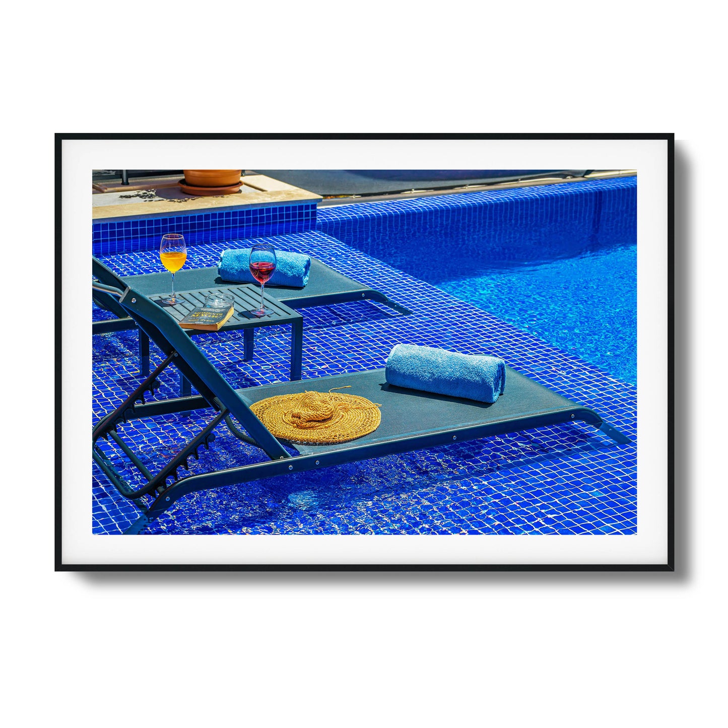 Poolside chairs with wine glasses and vibrant blue tiles.