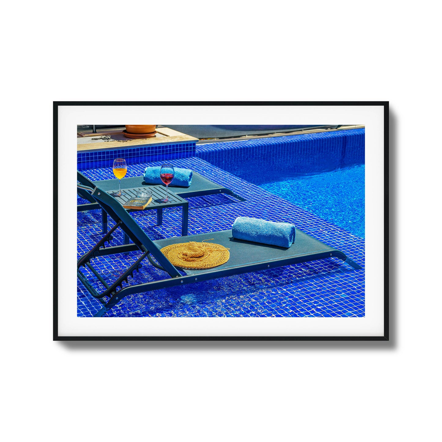 Poolside chairs with wine glasses and vibrant blue tiles.