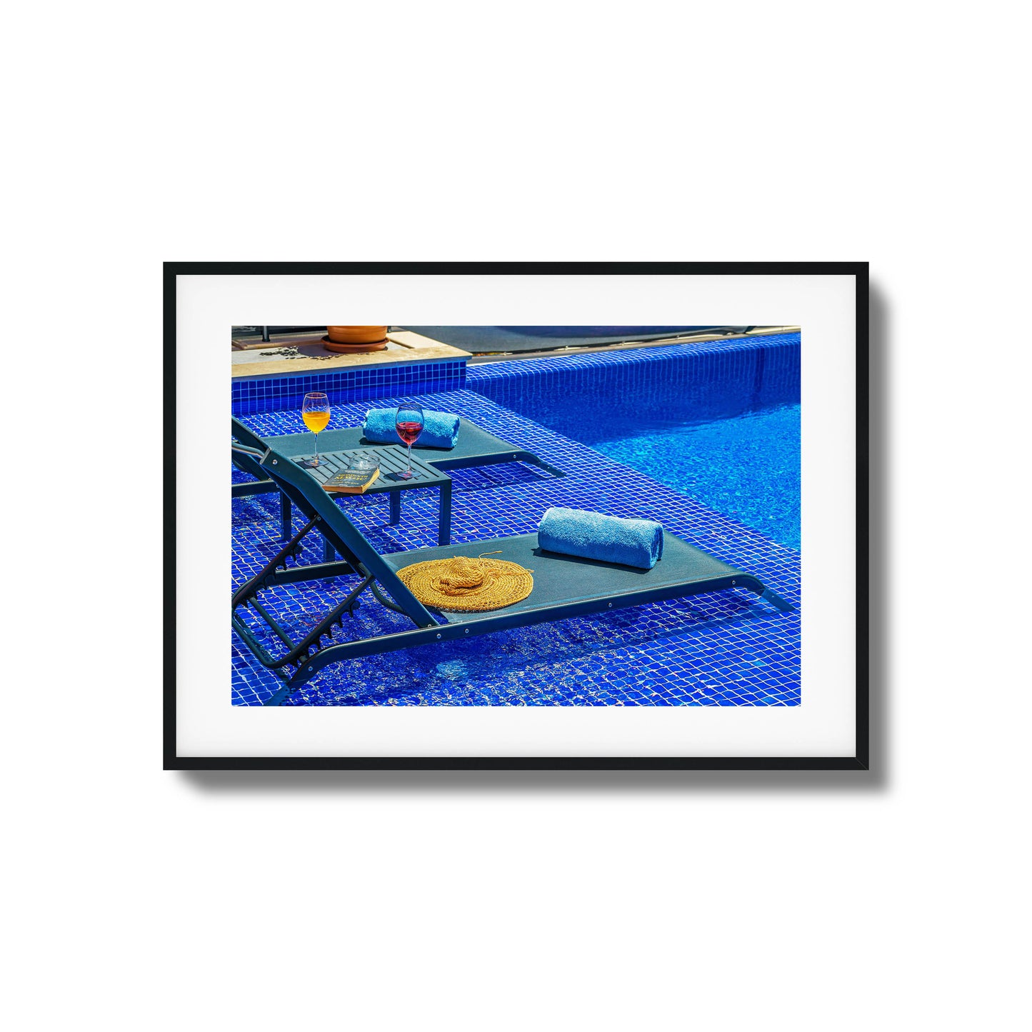 Poolside chairs with wine glasses and vibrant blue tiles.