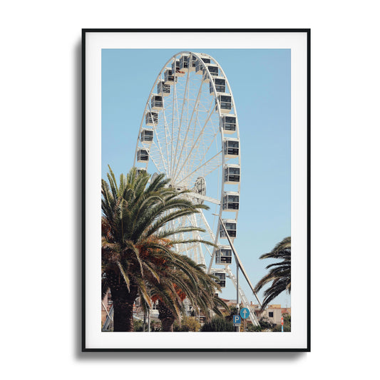 Ferris wheel and palm trees under a bright blue sky.