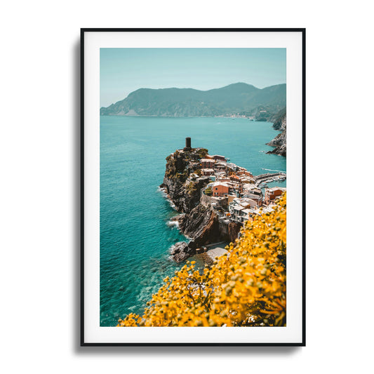 Coastal village on a cliff with turquoise waters and yellow flowers