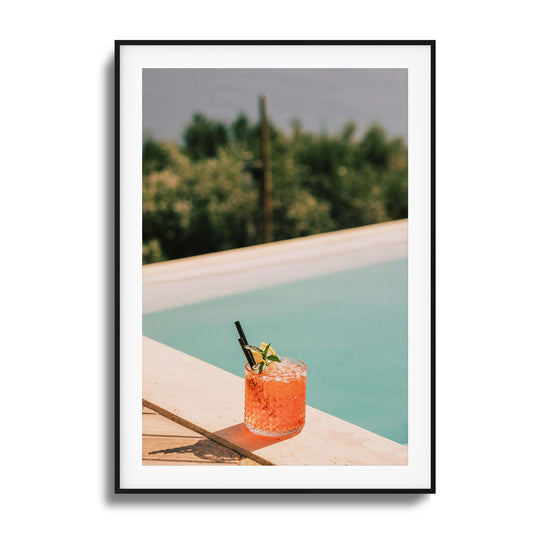 Crimson cocktail by a poolside ledge with sunlight.