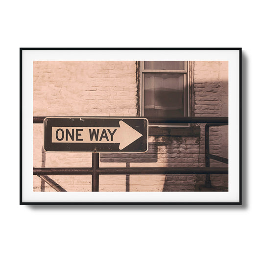 Weathered one-way street sign against a brick wall.