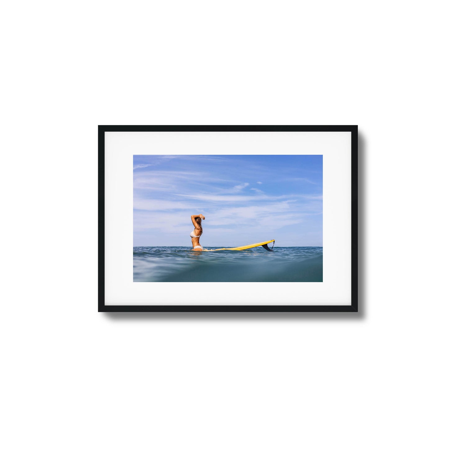 Woman with surfboard relaxing in open water framed art