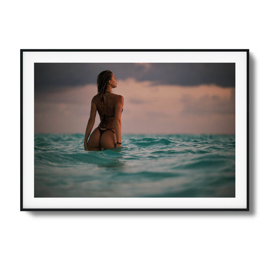 Woman standing in the ocean at dusk framed art