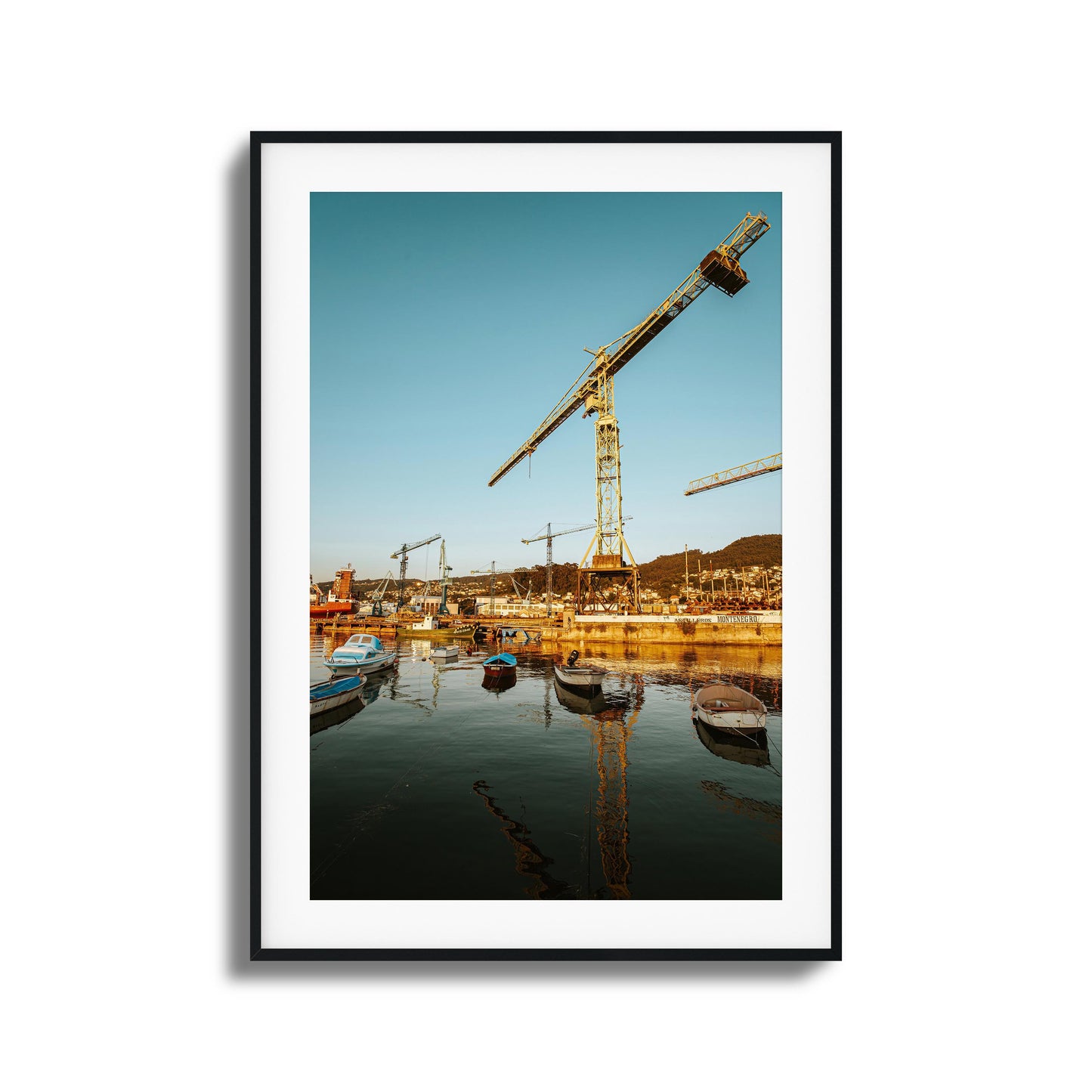 Boats and cranes lit by a rising sun over a harbor