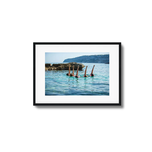 Synchronized swimmers with raised legs in turquoise waters framed art