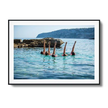 Synchronized swimmers with raised legs in turquoise waters framed art