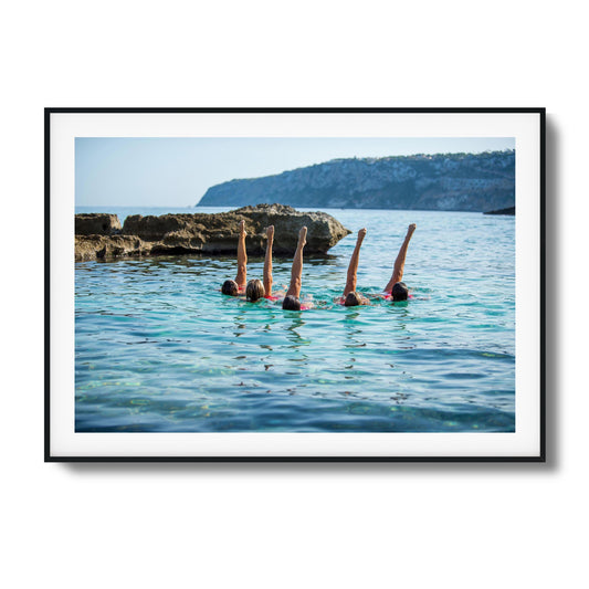 Synchronized swimmers with raised legs in turquoise waters framed art