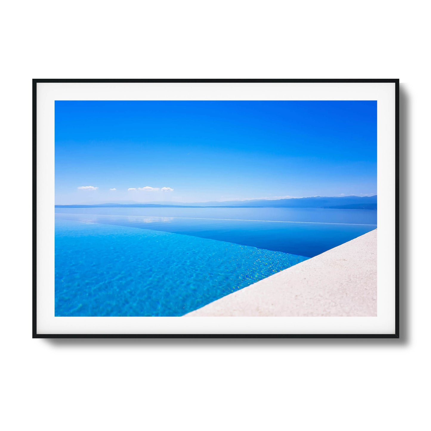 Infinity pool with crystal-clear blue water blending into the sea and distant mountains, framed art.