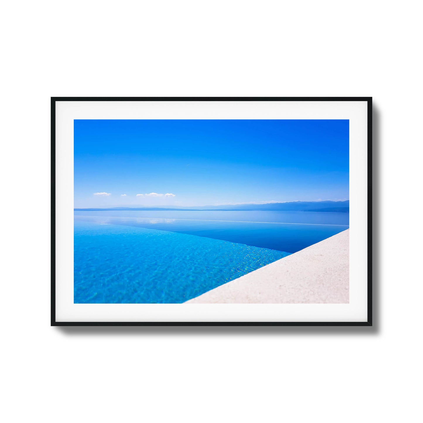 Infinity pool with crystal-clear blue water blending into the sea and distant mountains, framed art.