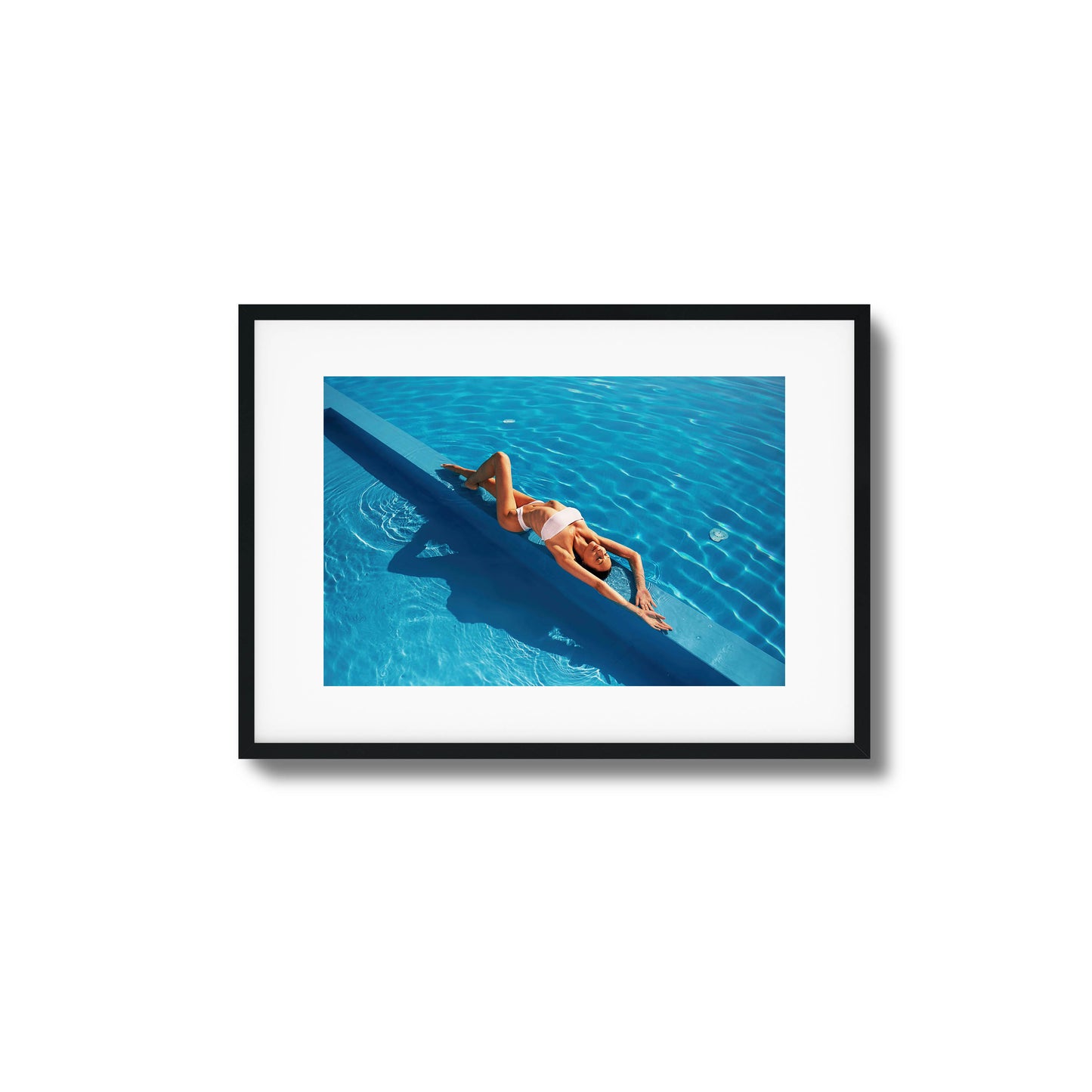 Woman relaxing poolside in bright blue water framed art