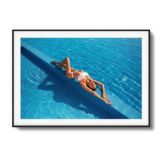 Woman relaxing poolside in bright blue water framed art