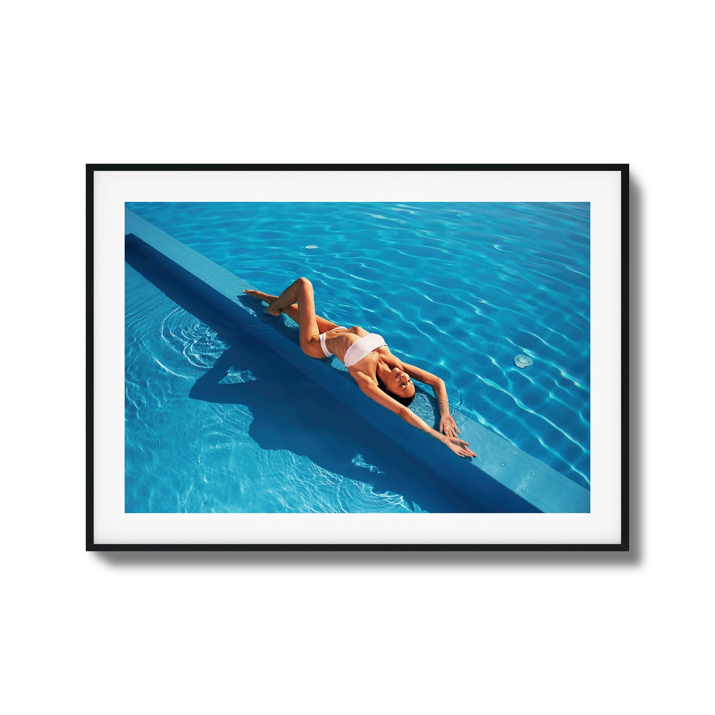 Woman relaxing poolside in bright blue water framed art