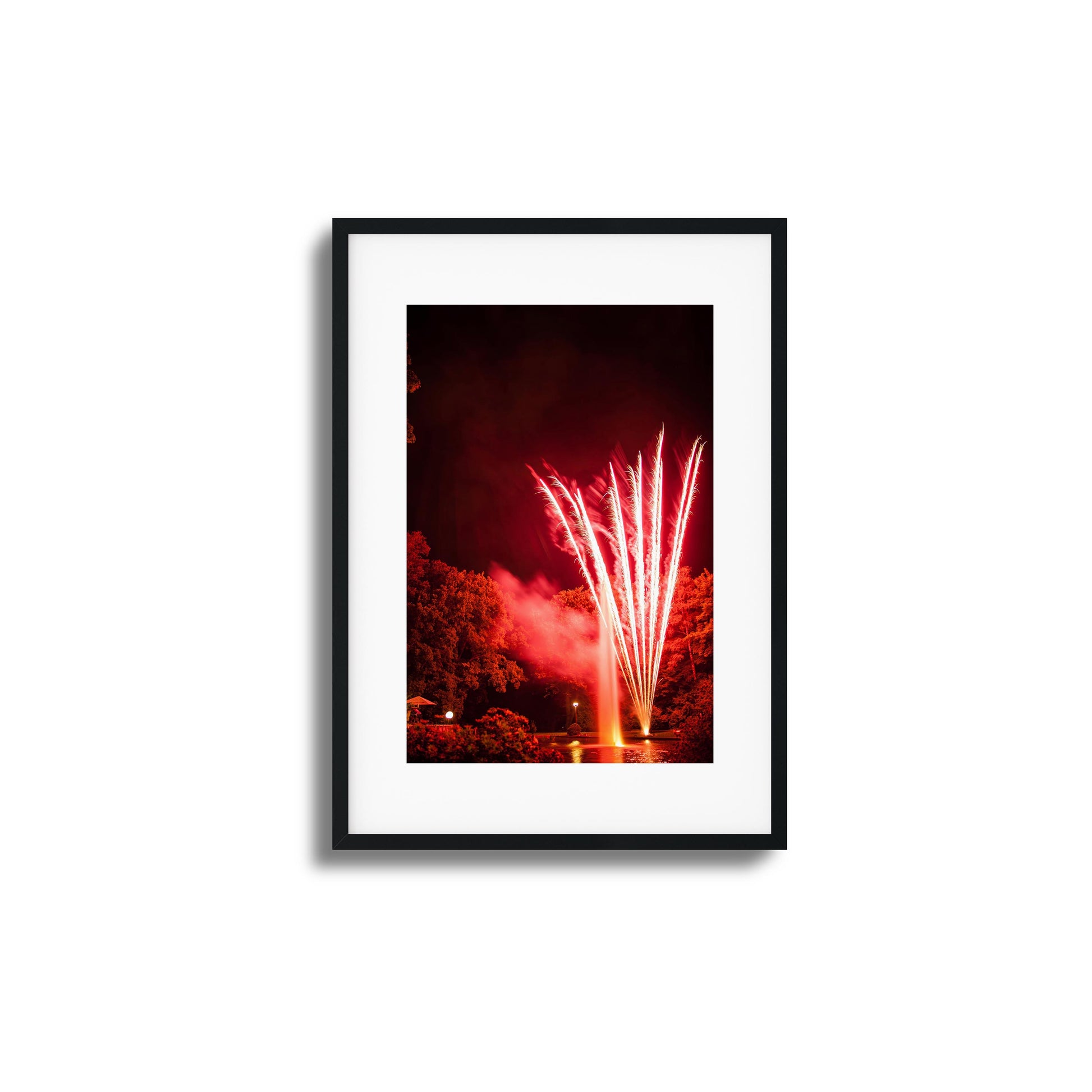 Red fireworks reflected in a pond at night