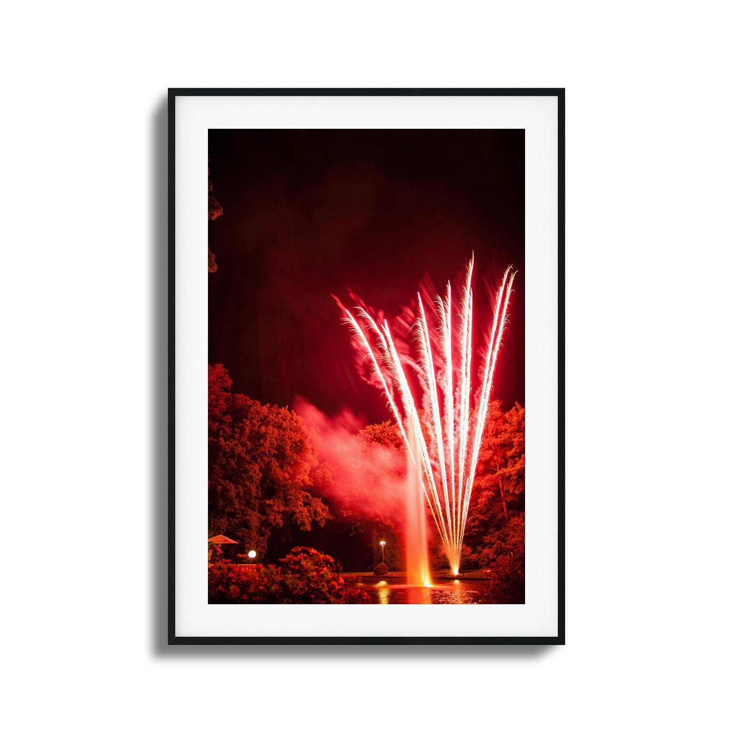 Red fireworks reflected in a pond at night