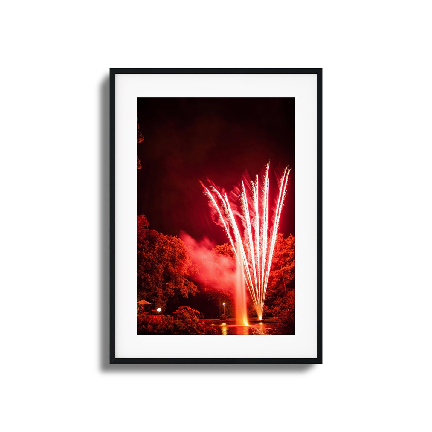 Red fireworks reflected in a pond at night