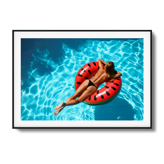 Framed artwork of a serene woman floating on a watermelon float in a clear blue pool.