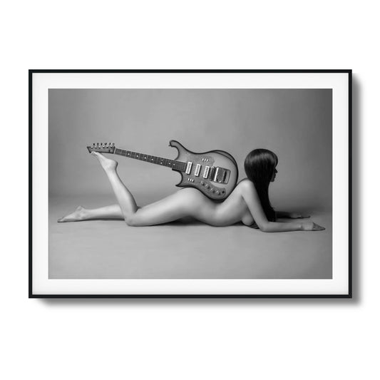 Black-and-white artistic photo of a figure lying with a guitar