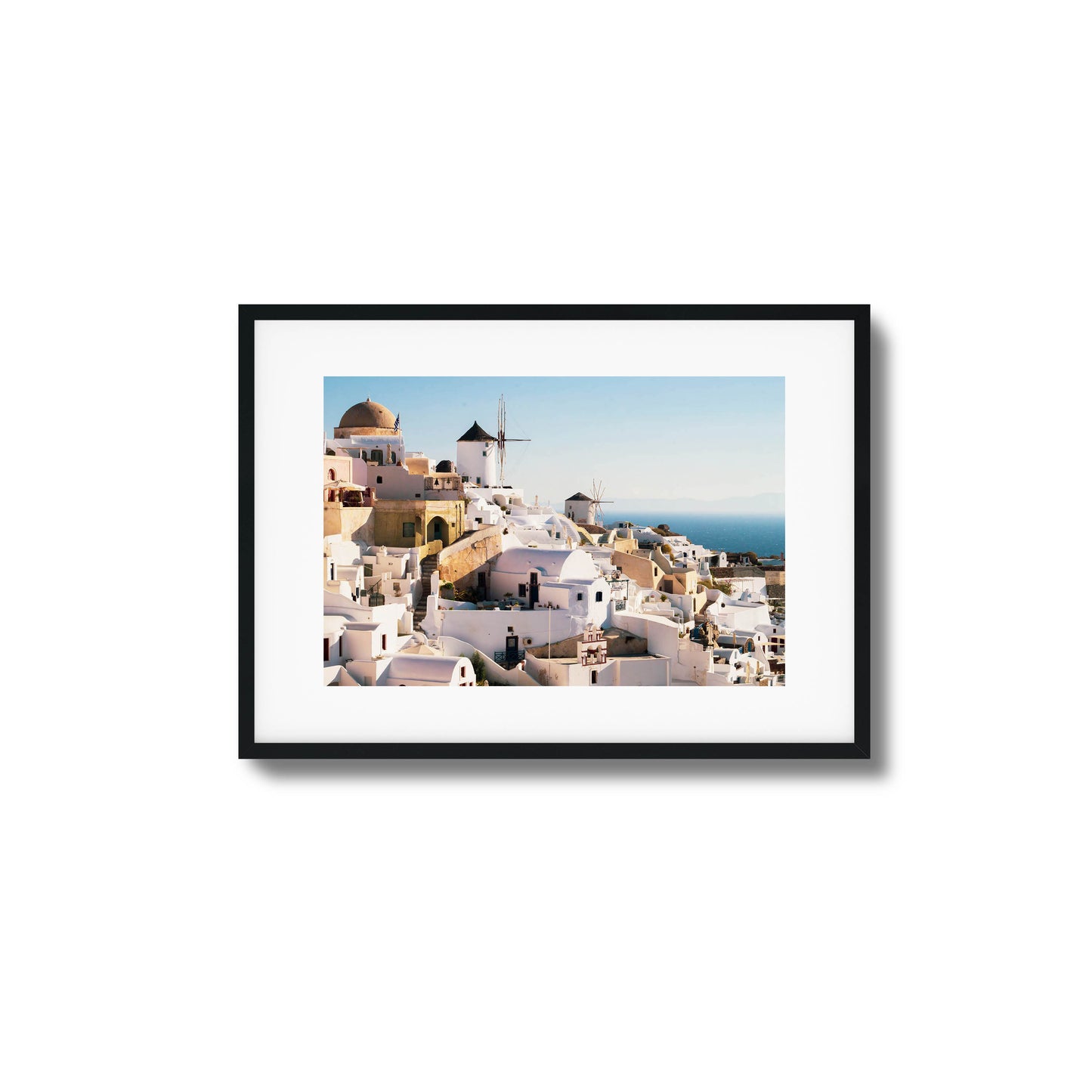 A stunning view of Santorini’s iconic white buildings and windmills under clear skies, framed art.