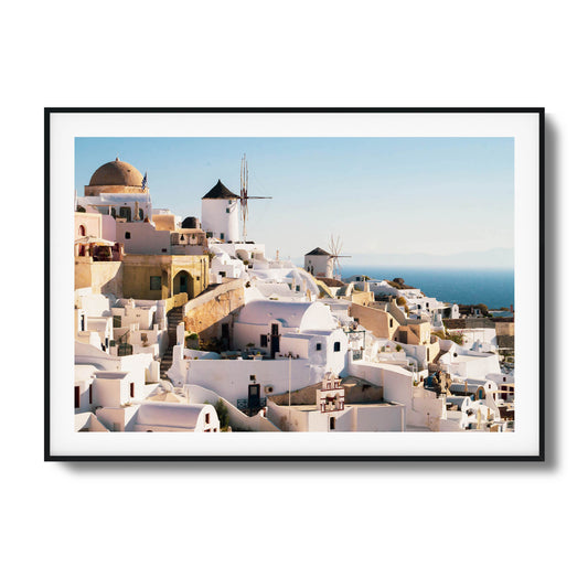 A stunning view of Santorini’s iconic white buildings and windmills under clear skies, framed art.