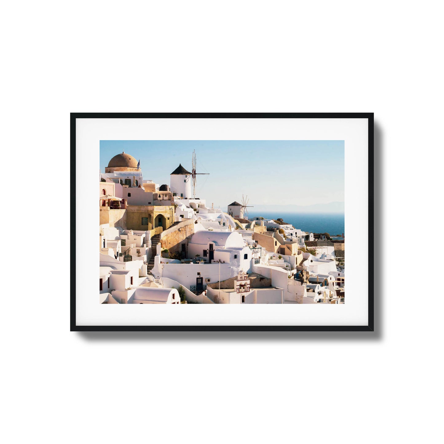 A stunning view of Santorini’s iconic white buildings and windmills under clear skies, framed art.