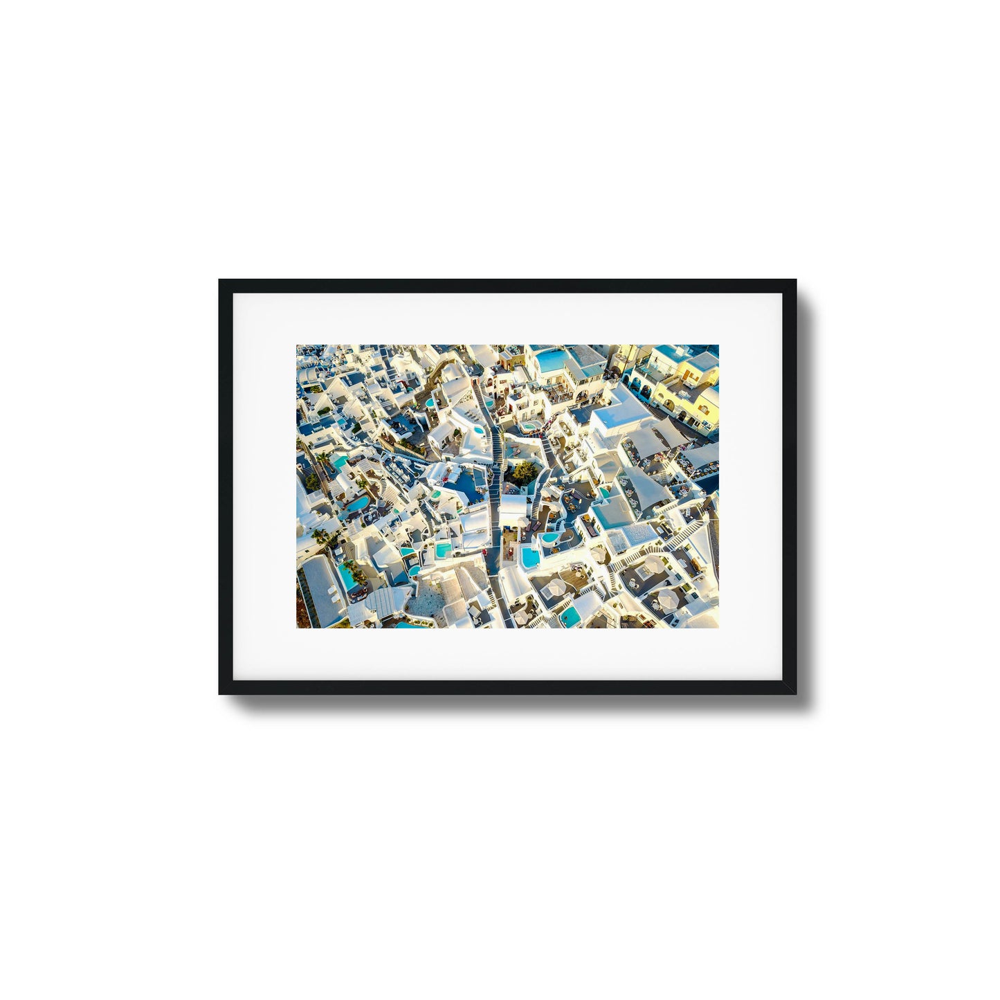 Aerial view of Santorini’s iconic white architecture with blue pools, ideal for framed wall art.