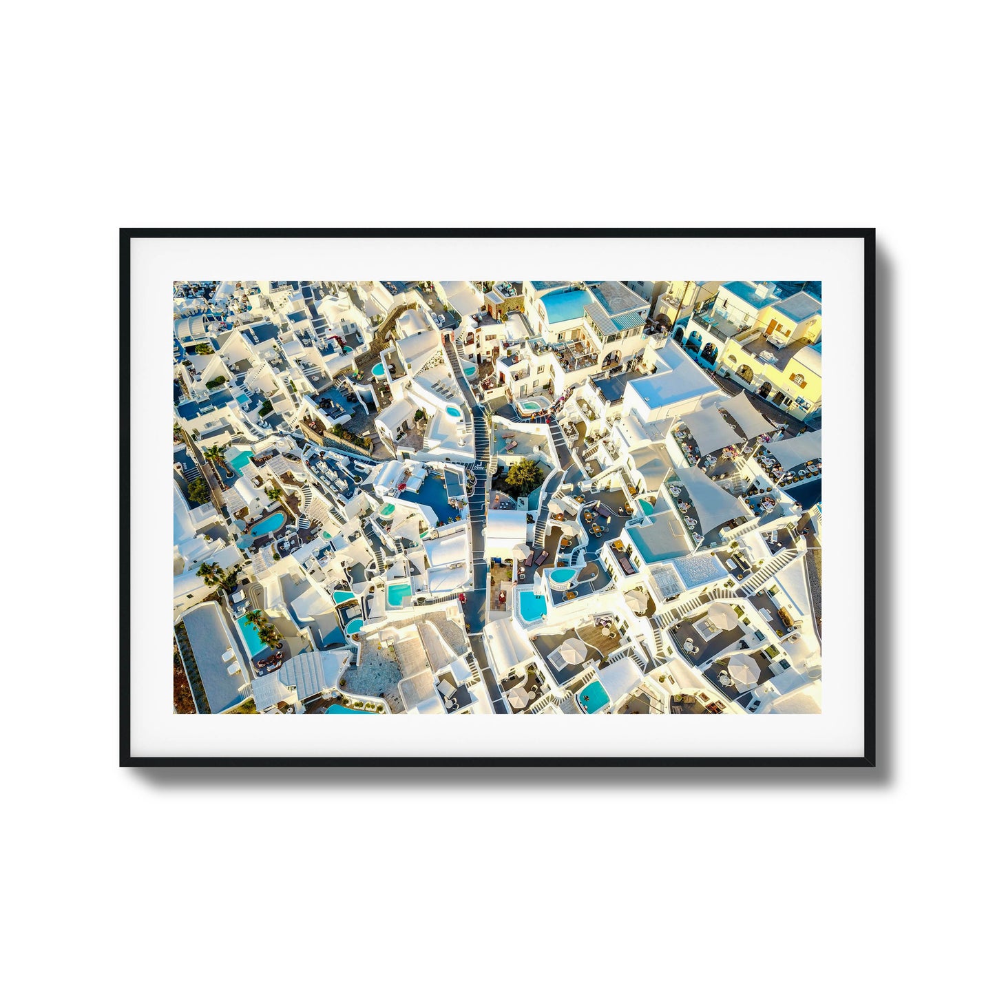 Aerial view of Santorini’s iconic white architecture with blue pools, ideal for framed wall art.