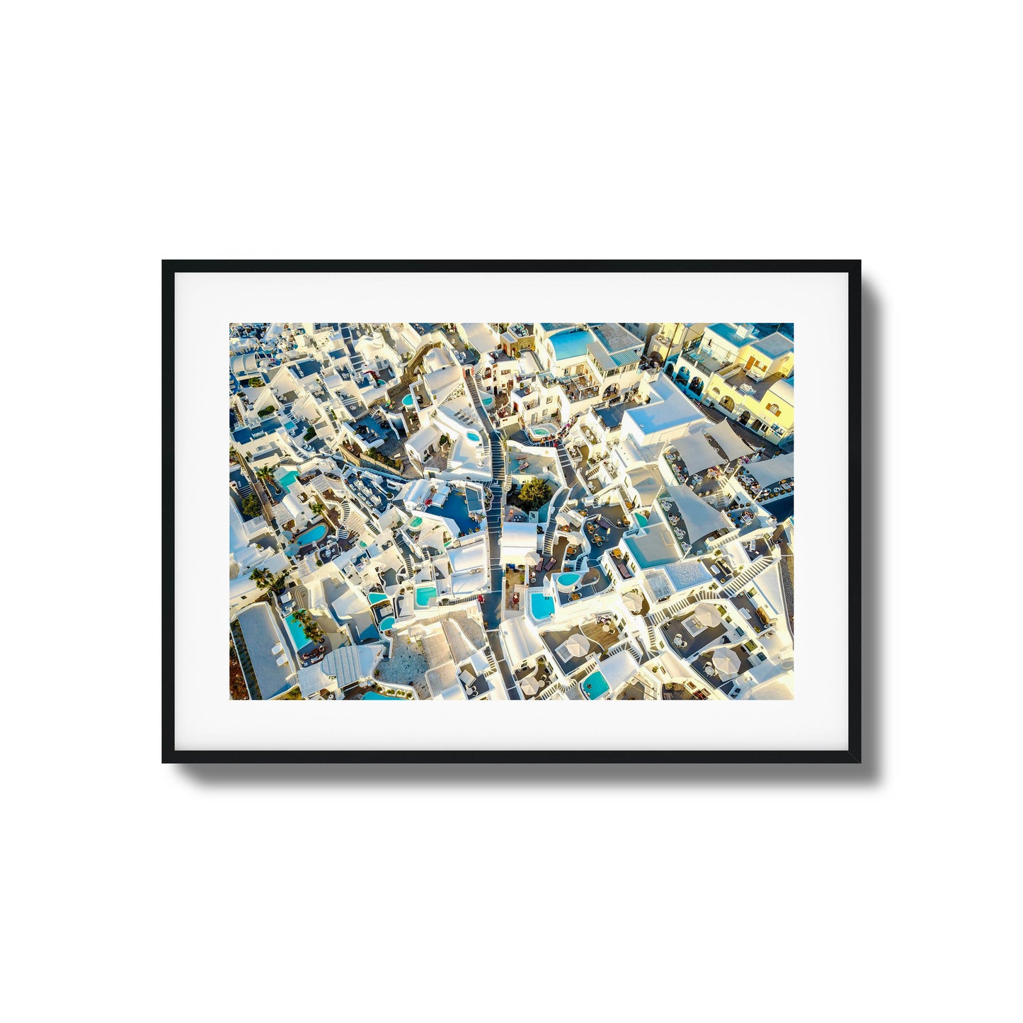 Aerial view of Santorini’s iconic white architecture with blue pools, ideal for framed wall art.