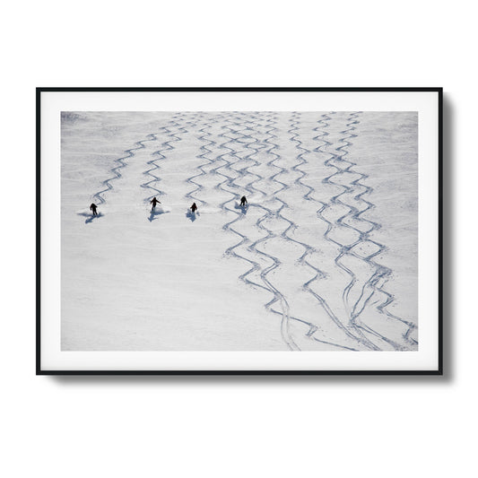 Skiers carving symmetrical tracks in snow framed artwork