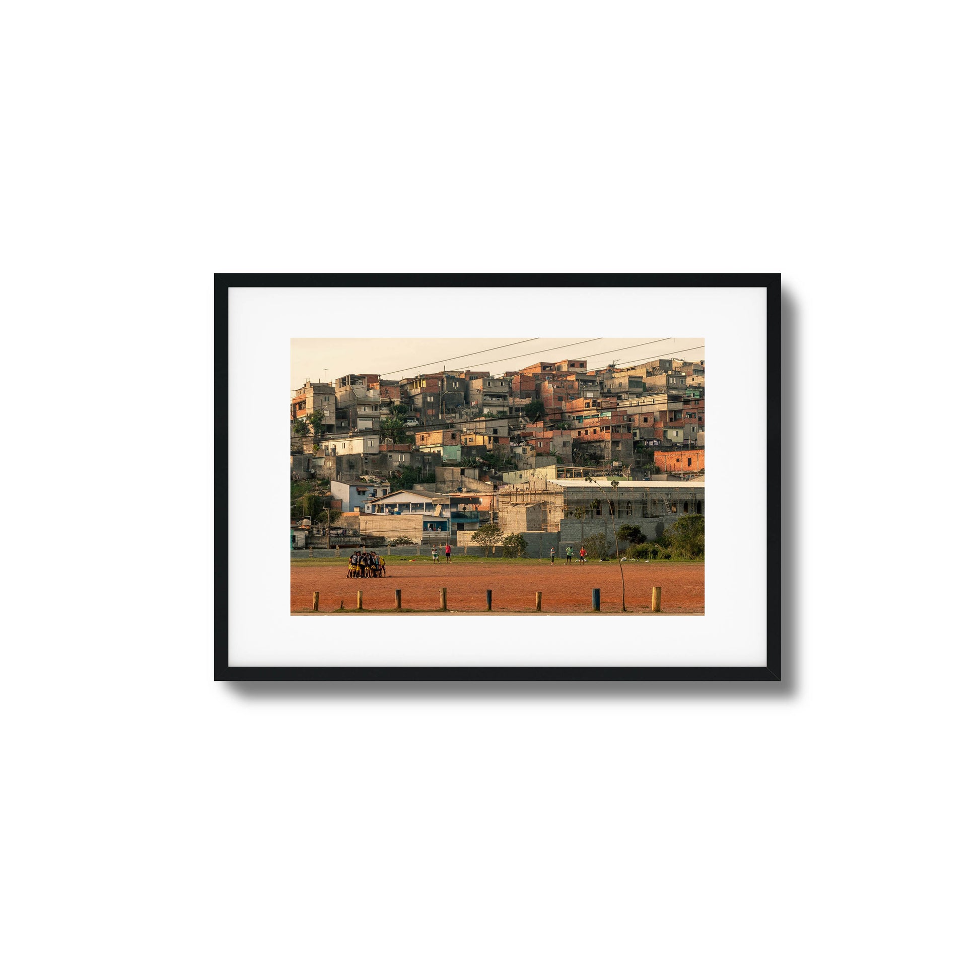 People huddled on a rust-colored field with houses.