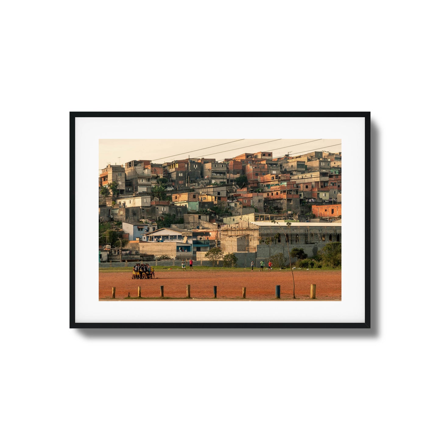 People huddled on a rust-colored field with houses.