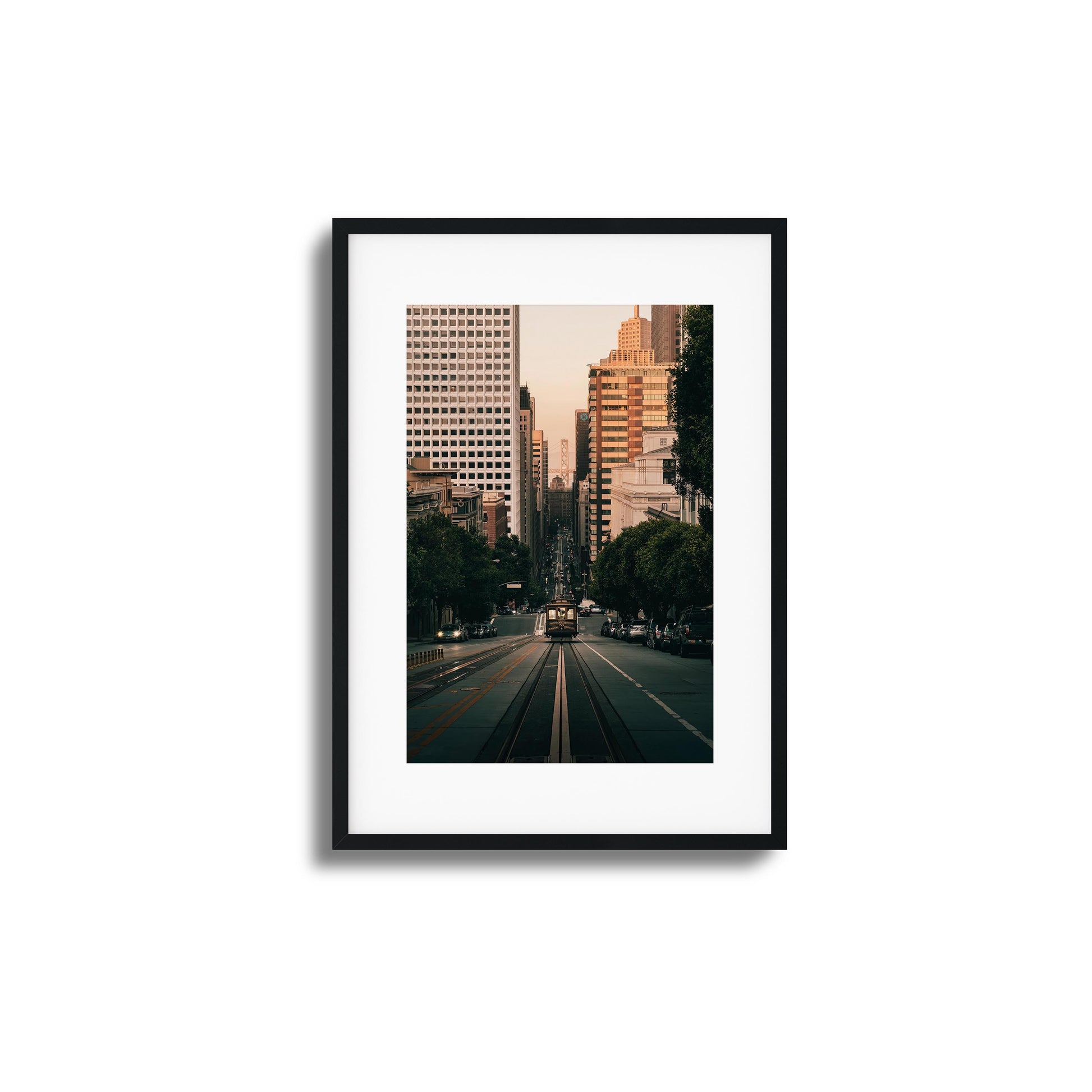 San Francisco cable car descending a hill with the city skyline in the background, framed art.