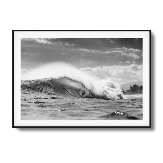 Surfer riding a large ocean wave in monochrome.