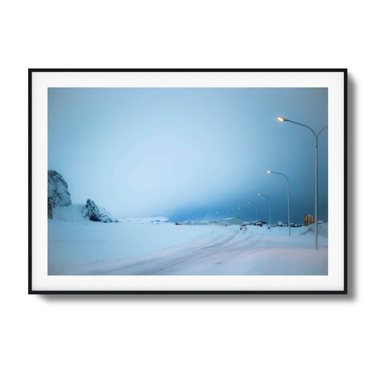 Snowy Icelandic landscape with glowing streetlights under a tranquil blue sky, perfect for framed art.