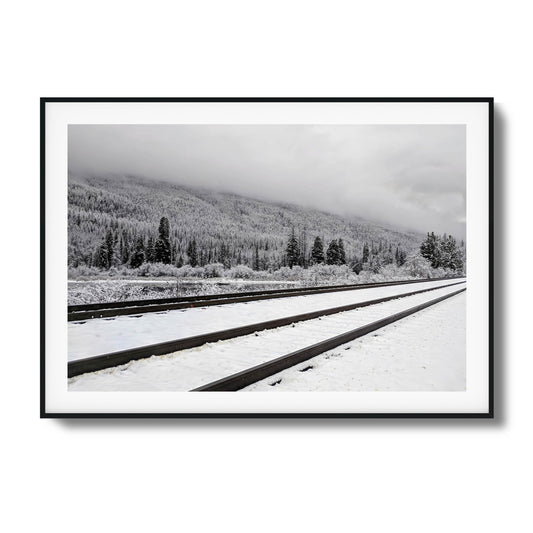 Snow-covered train tracks with misty forest backdrop